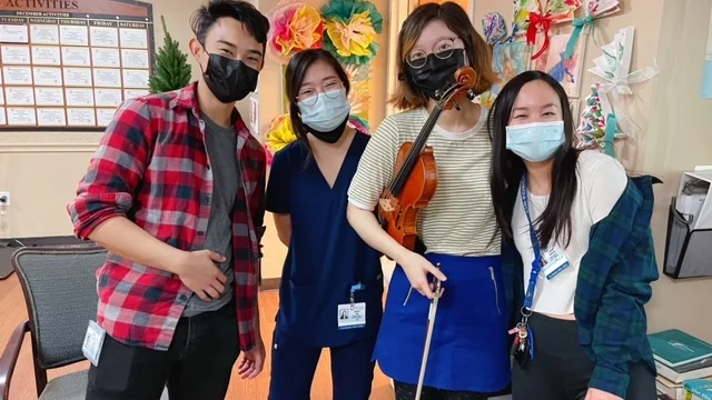 A group of medical students with string instruments in a medical facility